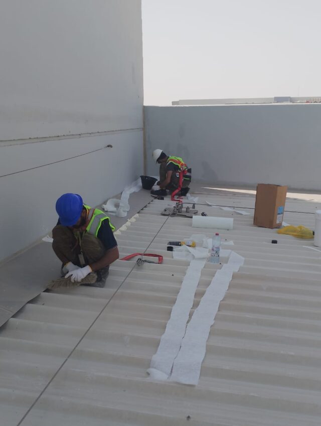 Professional waterproofing technicians applying membrane on a rooftop surface for long-term building protection.